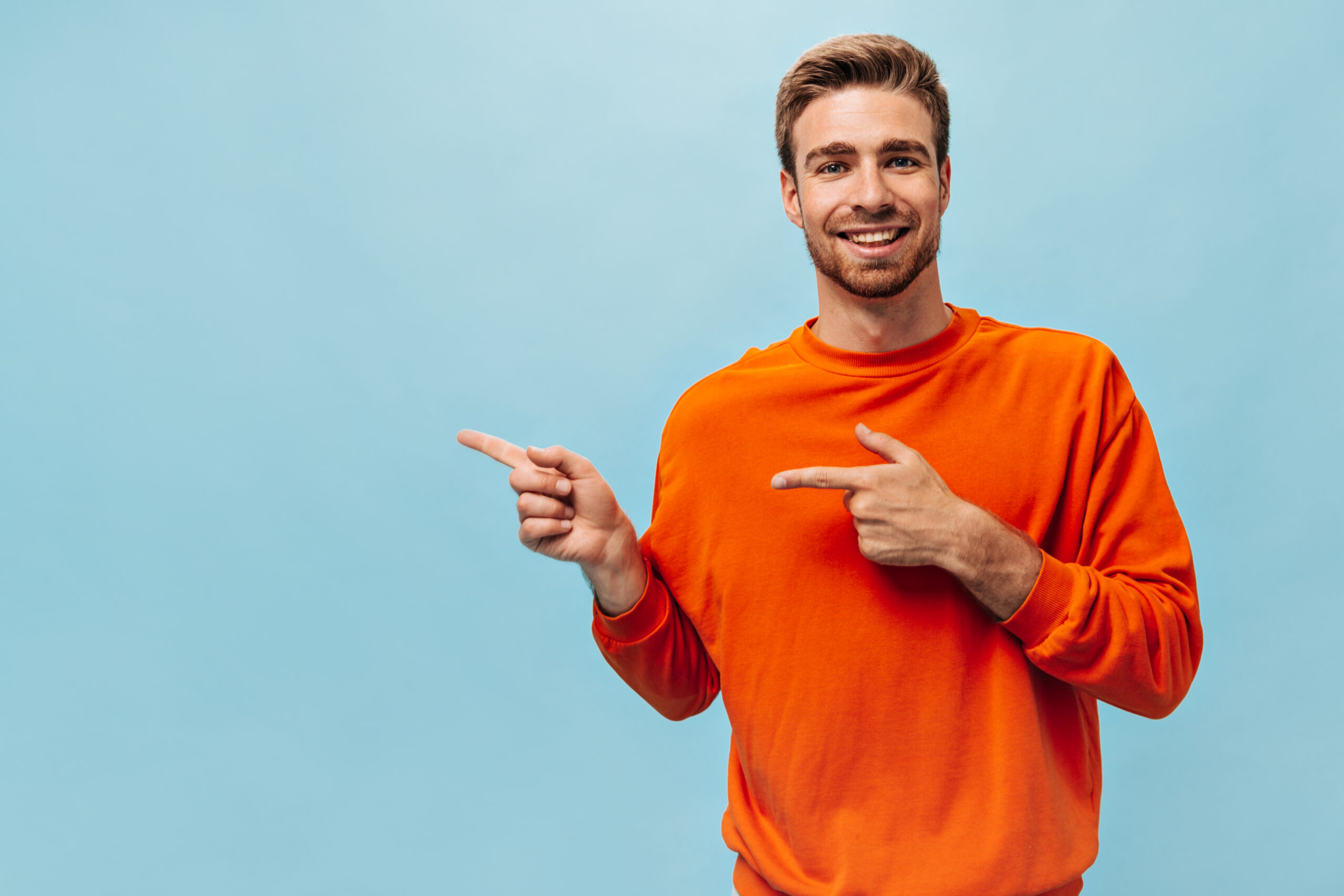 Homem sorrindo com camisa laranja.